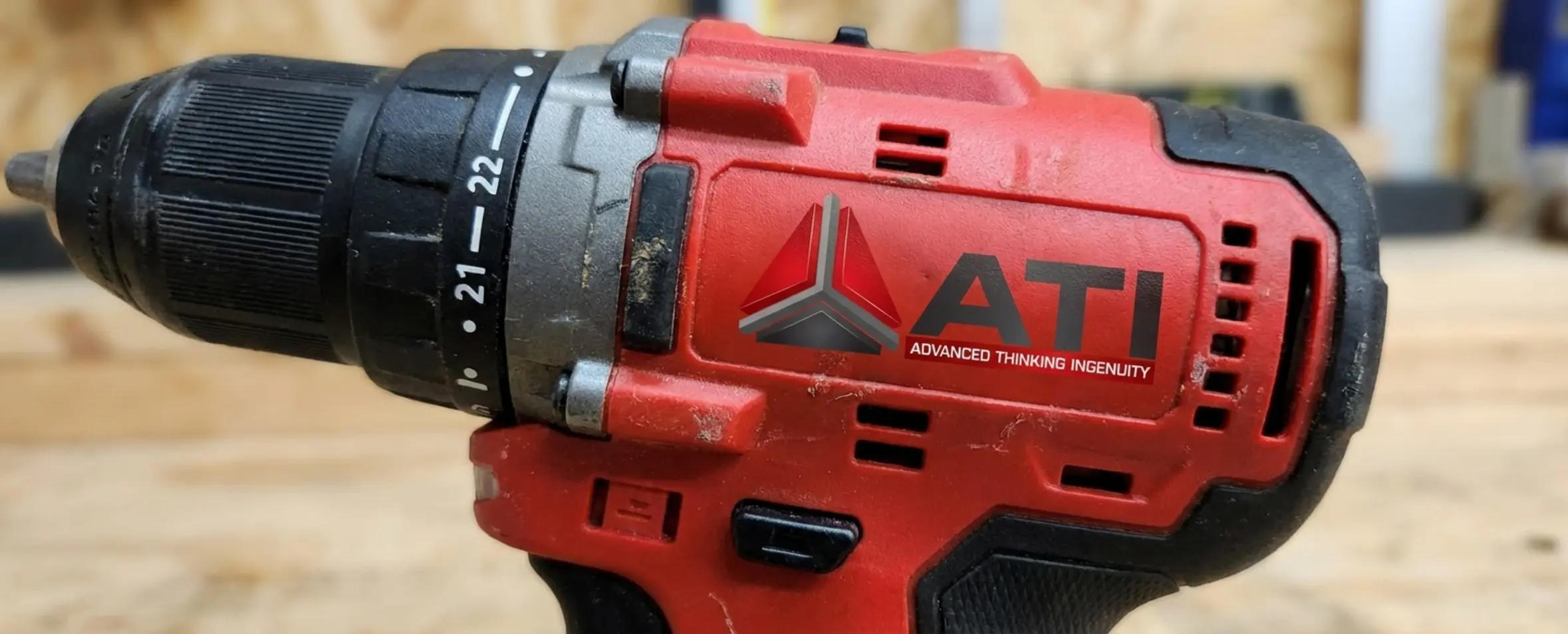 High-quality close-up of a power drill handle clearly showing the rigid red plastic and the textured black rubber wrapping the grip area